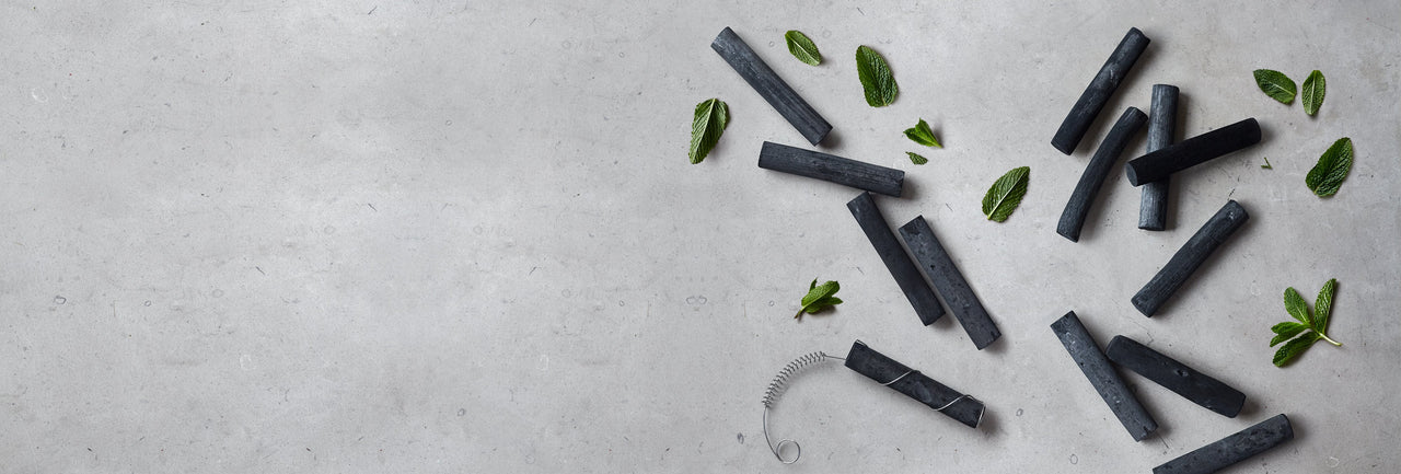 Active charcoal water filters with reusable water bottle on gray bench with mint leaves