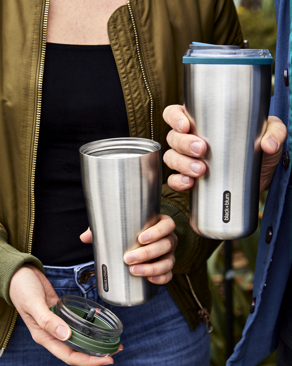 Two insulated travel mugs being held